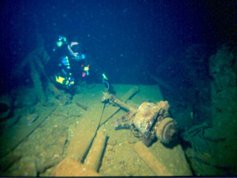 Andrew Whitehead examines an outboard motor and some propeller blades in Hold 1 of the Fujikawa Maru. Image by Neil Harris
